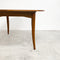 Wooden dining table on a concrete floor with a white wall background