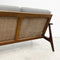 Wooden sofa with wicker backrest and gray cushions on a light background