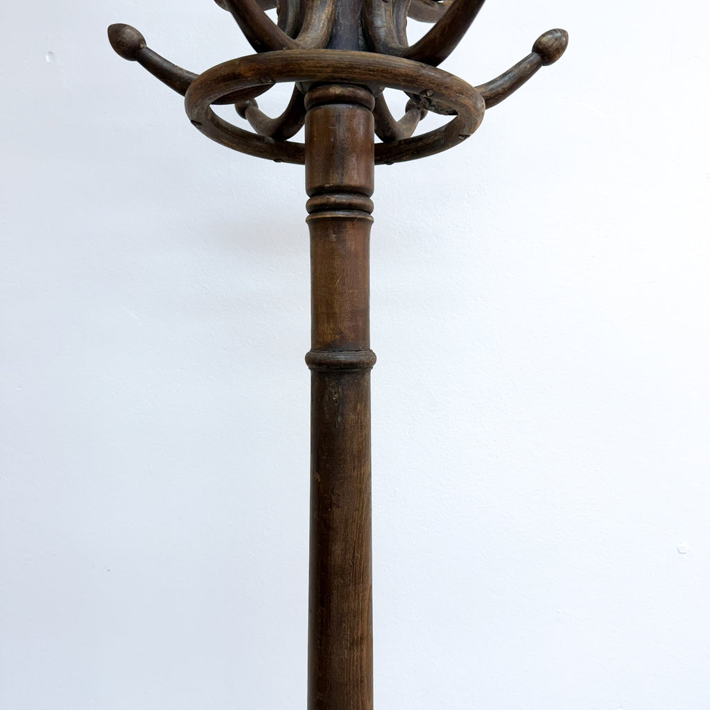 A dark brown wooden coat rack with a central post, a decorative ring, and multiple curved hanging arms, shown against a plain white background.