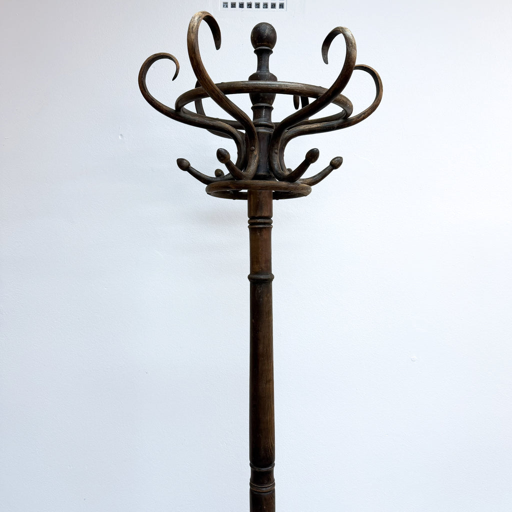 A vintage dark brown wooden coat rack with multiple curved hooks on a central pole, photographed against a plain white background.