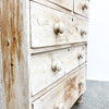 Wooden dresser with white-painted finish and visible grain texture.