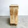 Wooden cabinet with a rustic finish on a concrete floor against a white wall