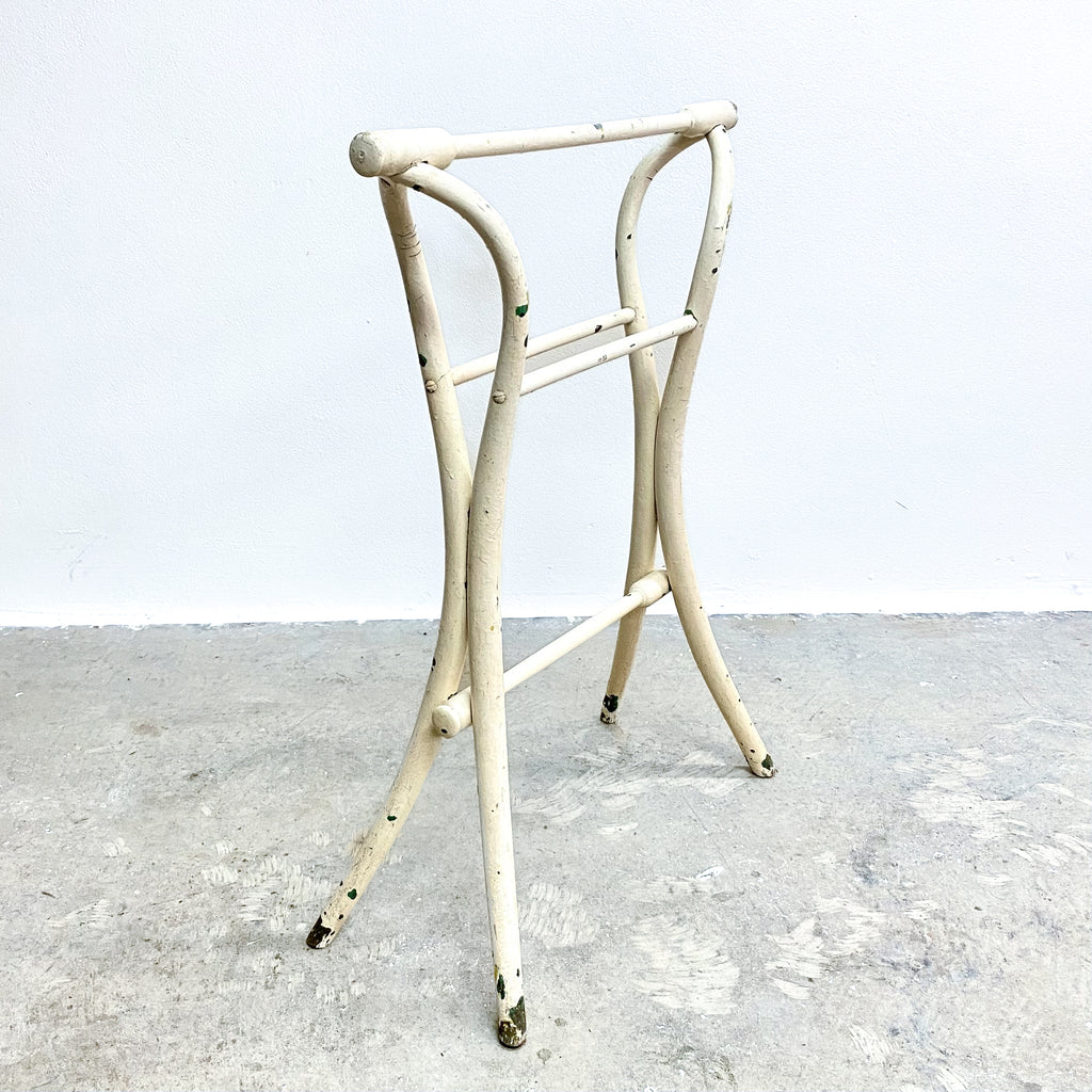 White metal stool with a minimalist design on a gray concrete floor.