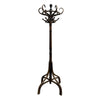 A dark brown wooden coat rack with a multi-hook top and a tripod-style base, standing on a concrete floor against a plain white wall.