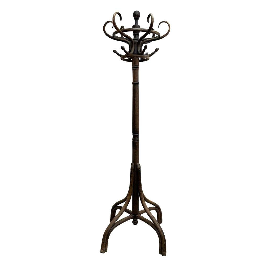 A dark brown wooden coat rack with a multi-hook top and a tripod-style base, standing on a concrete floor against a plain white wall.