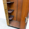Close-up of the interior corner of a wooden cabinet or shelf unit with three dark wooden shelves and a floral-patterned side panel.
