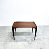 Wooden table with black legs on a textured white floor