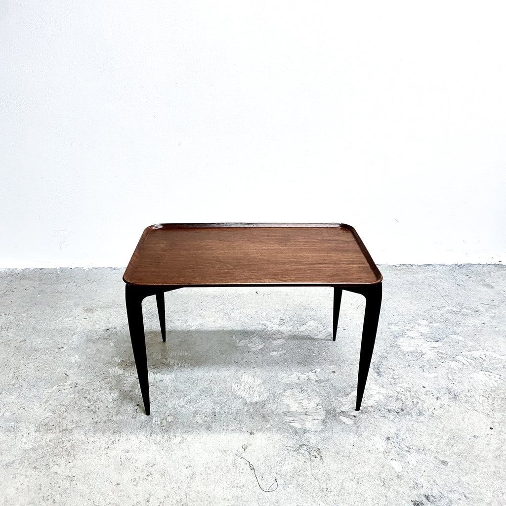 Wooden table with black legs on a textured white floor