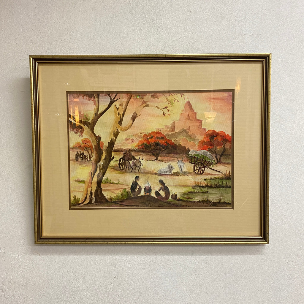 Framed artwork of a landscape scene with people and a tree on a white wall.