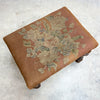Small ottoman with floral pattern on a light gray background