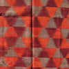 A close-up of a woven textile with a repeating geometric pattern of orange, rust red, and taupe-brown triangles.