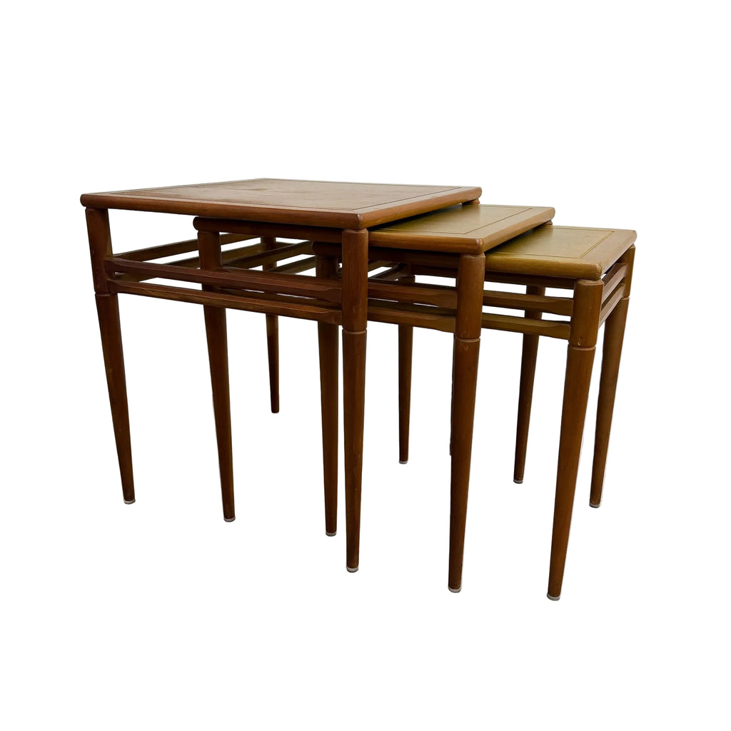 Three nested wooden nesting tables  photographed against a plain white wall and concrete floor.