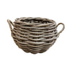A round woven wicker basket with two twisted side handles, shown on a light gray concrete floor against a white wall.