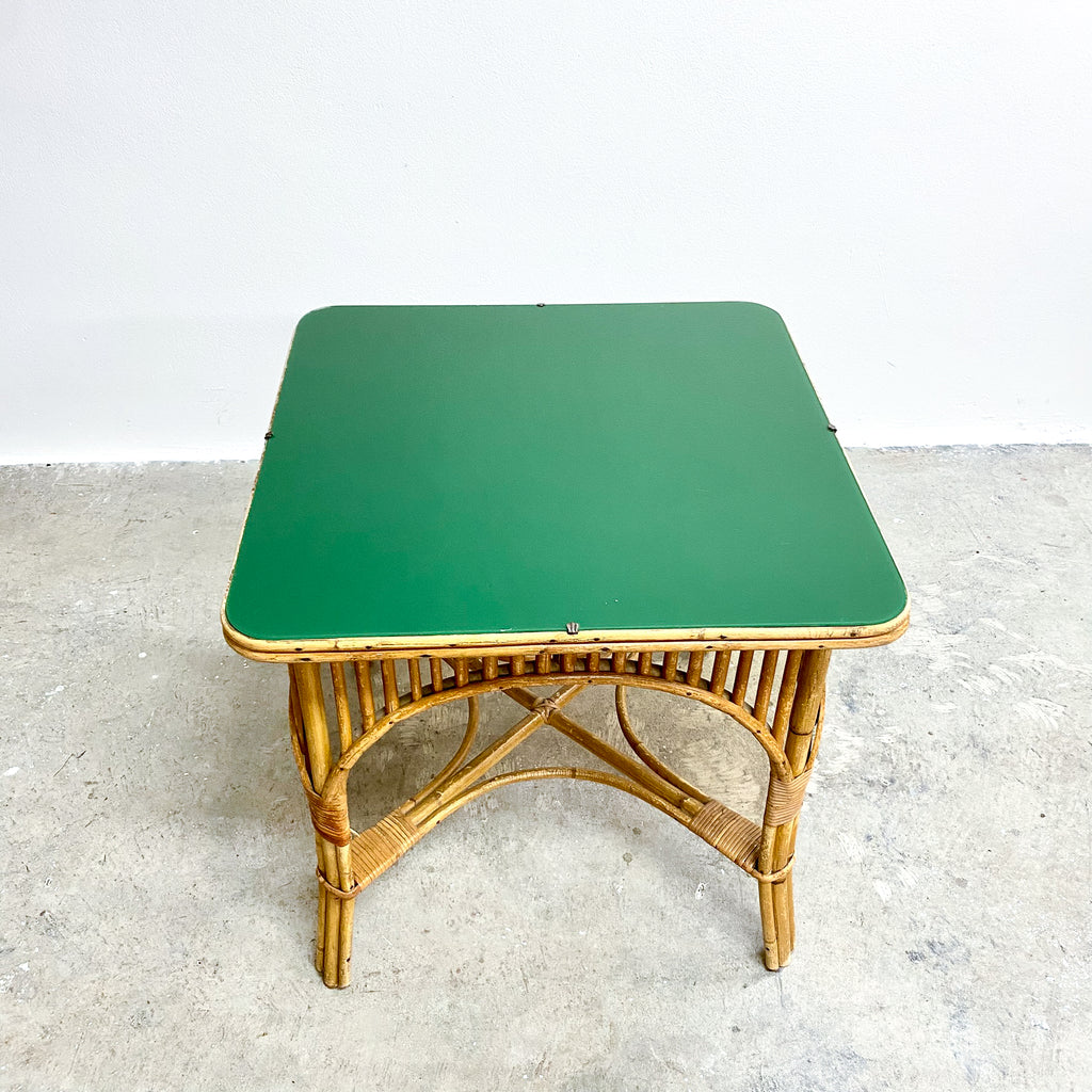 Green table with wicker base on a light gray surface