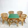 Wicker chairs and a green table on a concrete floor with a white wall background