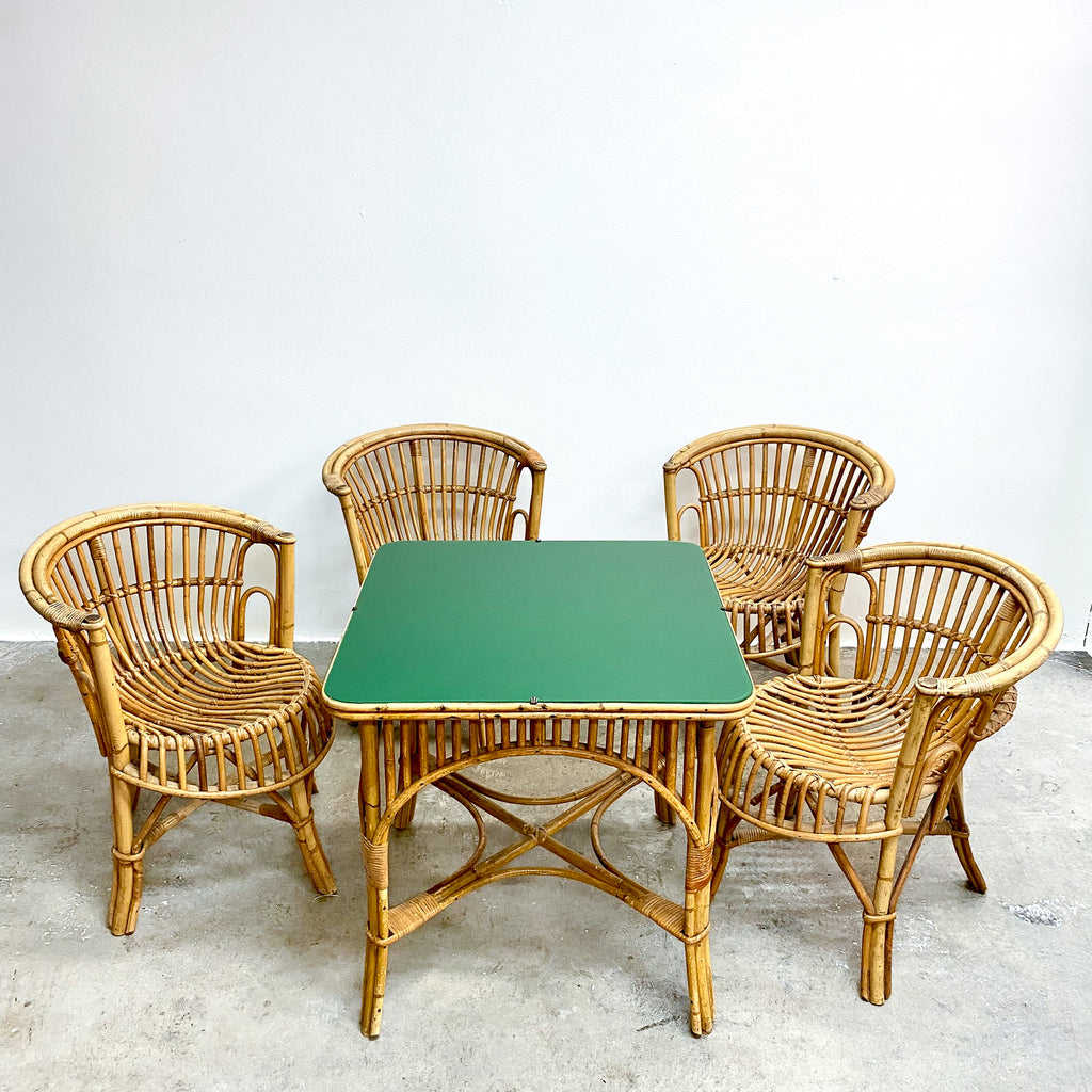 Wicker chairs and a green table on a concrete floor with a white wall background