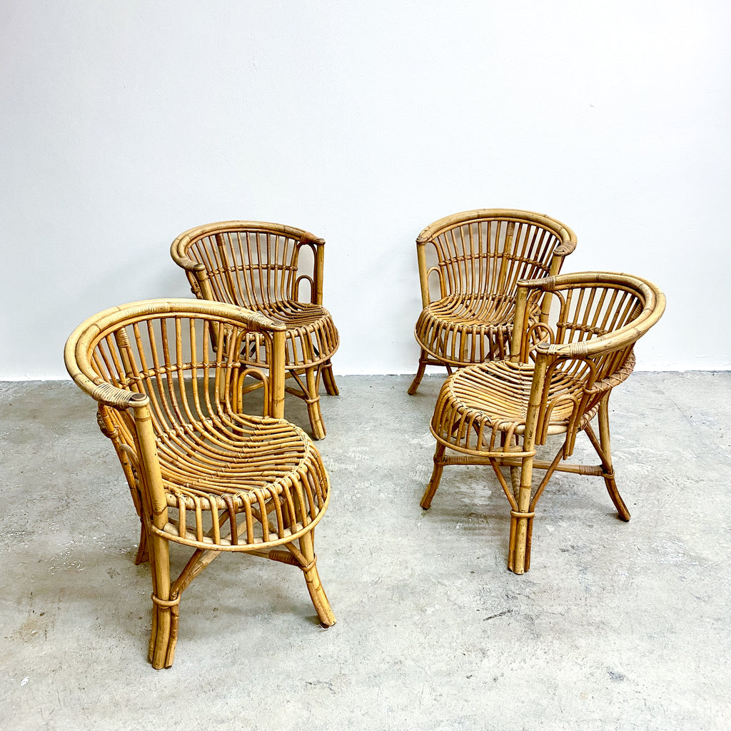 Four wicker chairs on a concrete floor with a white wall background