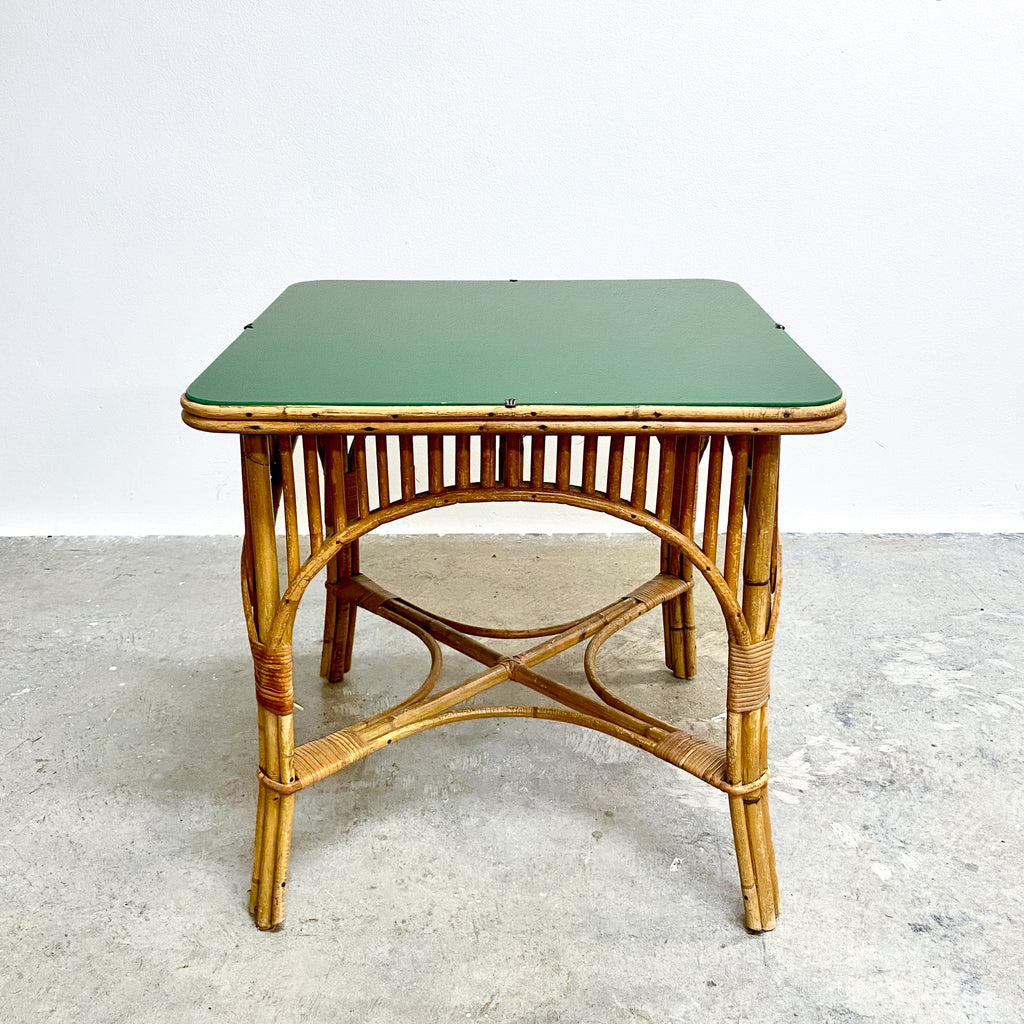 Green table with a wicker frame on a concrete floor