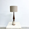 Table lamp with a wooden base and beige shade on a marble surface.