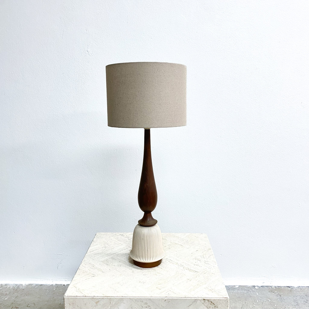 Table lamp with a wooden base and beige shade on a marble surface.
