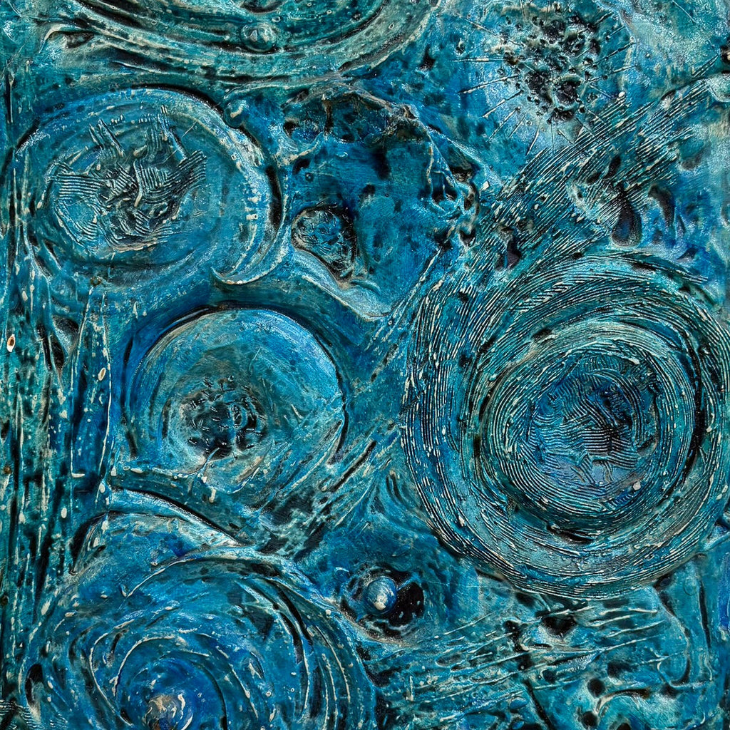 An abstract textured painting featuring swirling circular patterns in shades of teal, blue, and green, mounted on a white wall.
