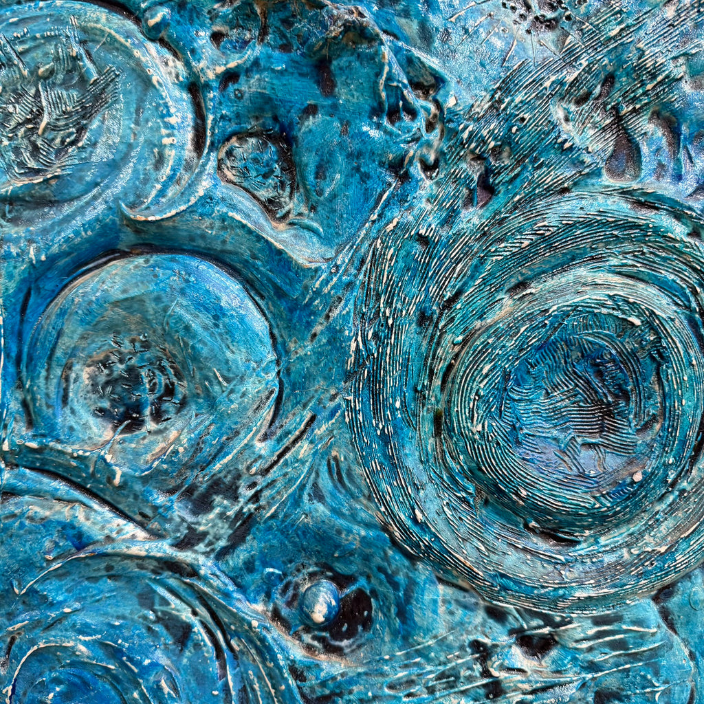 Abstract textured artwork featuring swirling and concentric organic patterns in shades of blue, teal, and turquoise with metallic and glossy highlights.