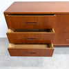 Mid-century modern wooden credenza or dresser with three drawers on the left and open drawers, shown on a concrete floor against a white wall.