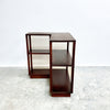 Set of three wooden side tables on a textured white surface with a light gray background