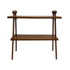 A mid-century modern wooden console table with two shelves, featuring tapered legs and decorative round finials on the top corners, set against a plain white wall and concrete floor.