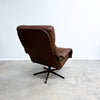Brown leather swivel chair on a gray floor with a white wall background