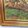 A close-up of a framed painting showing textured impasto brushstrokes in green, orange, brown, and gold tones, with a prominent gold wooden frame.