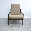 Beige armchair with wooden frame on a gray floor and light blue wall