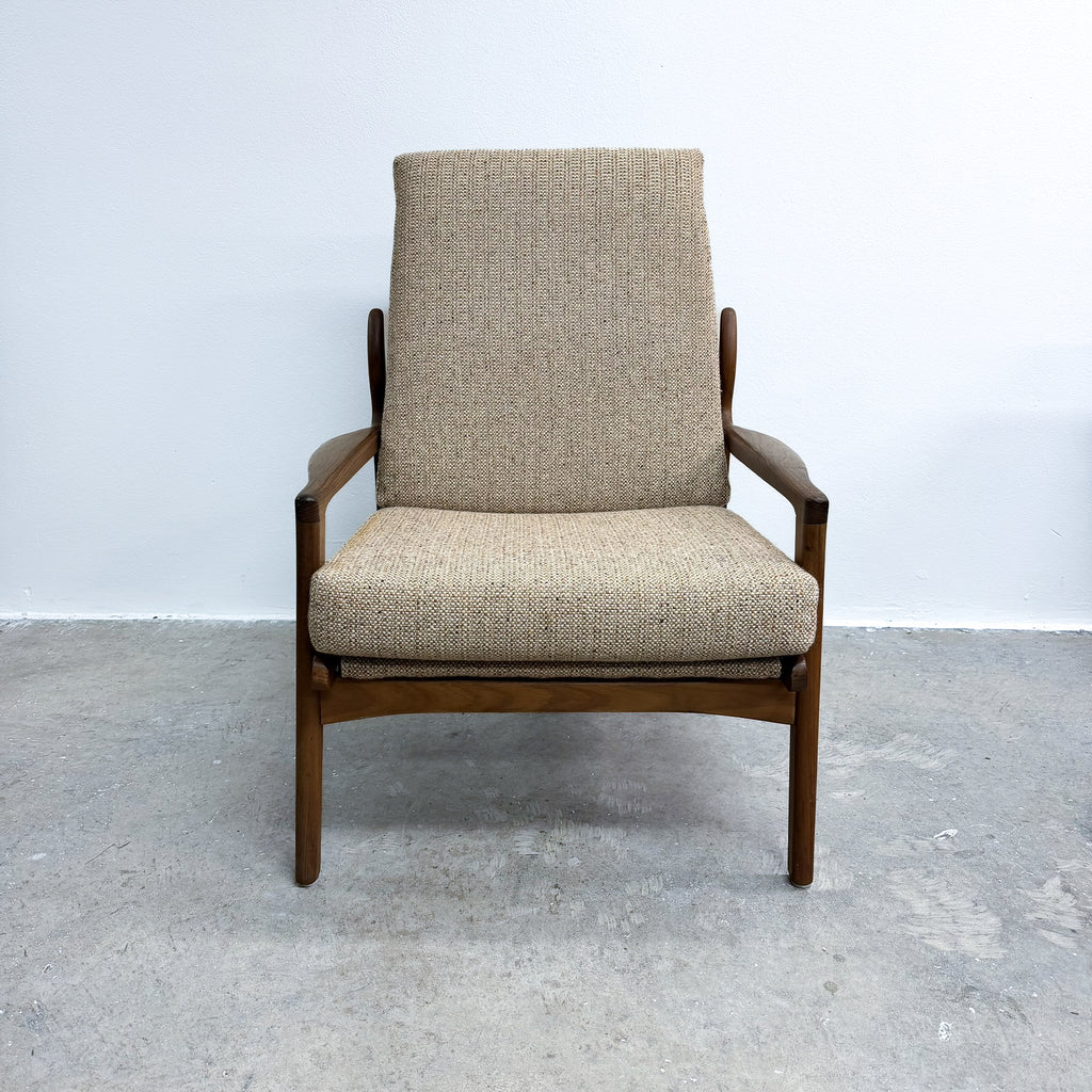 Beige armchair with wooden frame on a gray floor and light blue wall