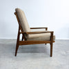 Wooden armchair with beige cushion on a gray floor and white wall background