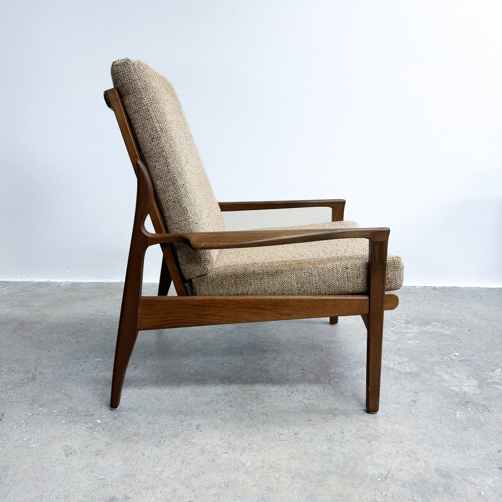 Wooden armchair with beige cushion on a gray floor and white wall background