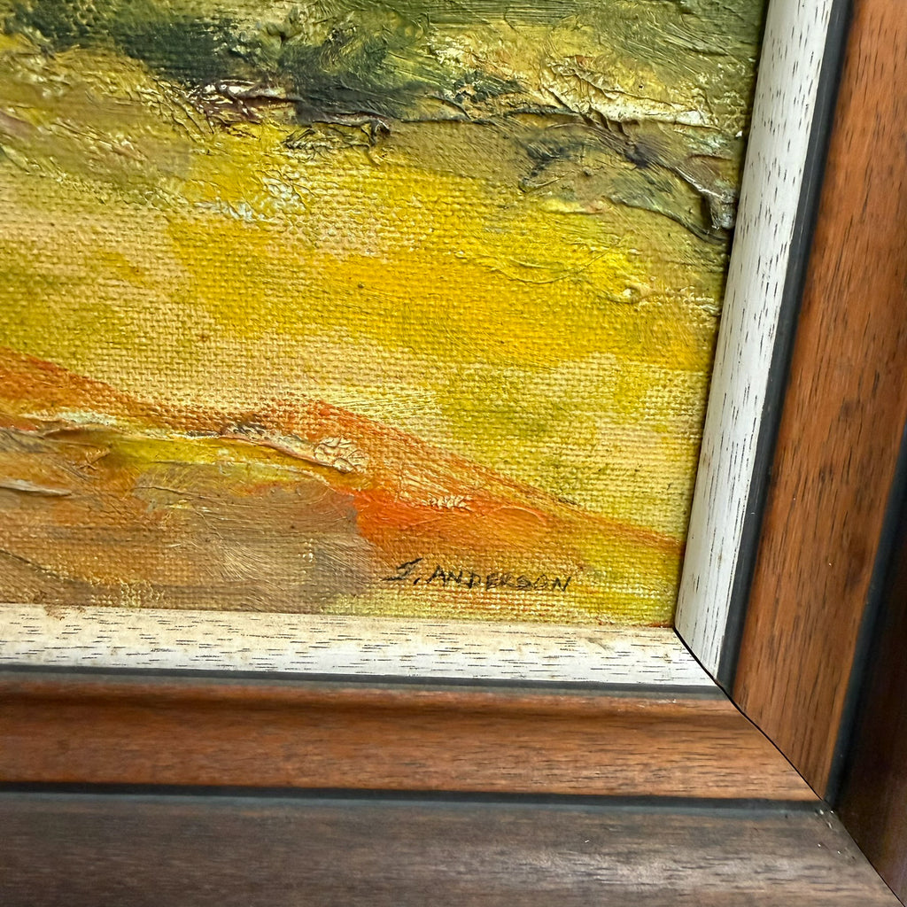 Close-up of a framed painting showing textured impasto brushstrokes in yellow, green, orange, and brown, with a visible artist signature near the bottom.