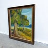 A framed landscape oil painting depicting green trees and a grassy field under a blue sky, housed in a dark brown wooden frame and leaning against a white wall on a gray concrete floor.
