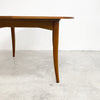 Wooden dining table on a concrete floor with a white wall background