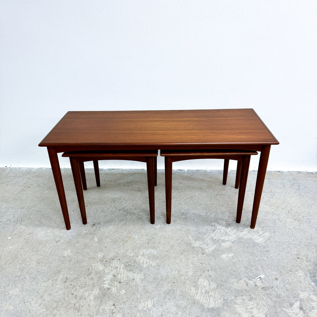 Wooden dining table set on a textured white floor with a plain white wall background