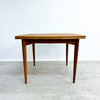 Wooden dining table with a white wall and gray floor background