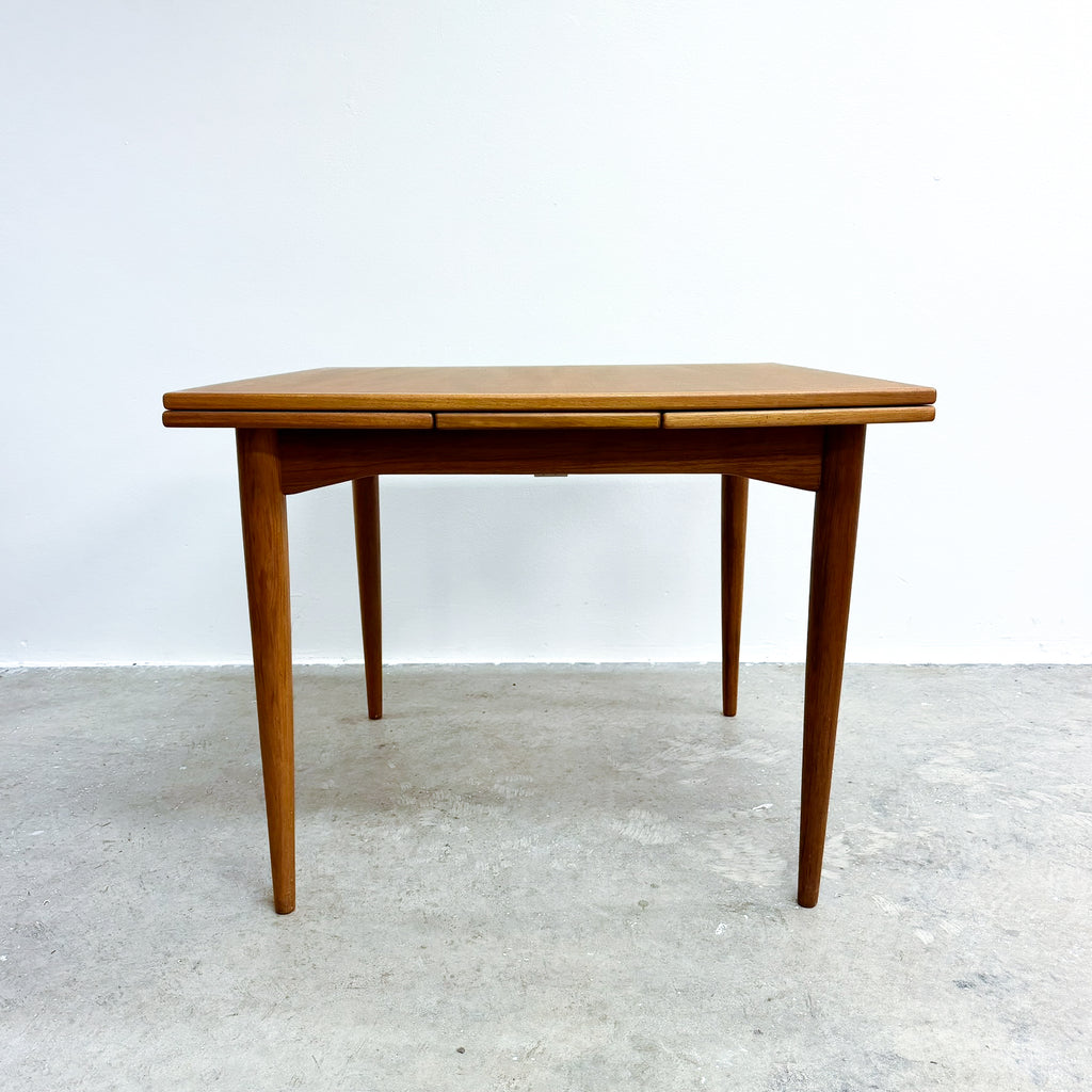 Wooden dining table with a white wall and gray floor background