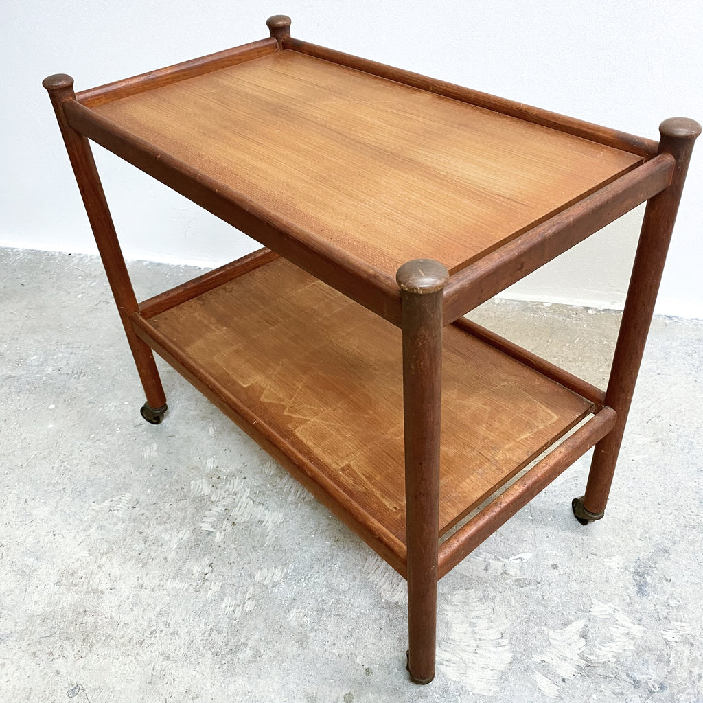 Wooden side table with two shelves on a concrete floor.
