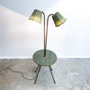 Floor lamp with two green shades on a concrete floor against a white wall