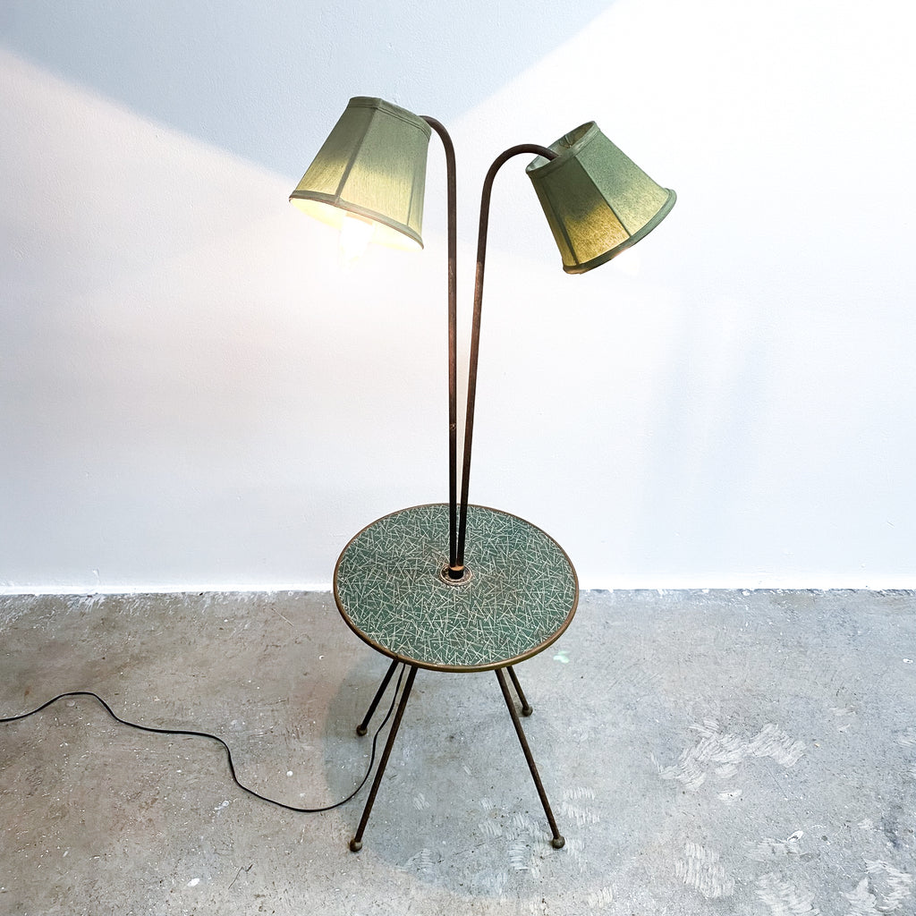 Floor lamp with two green shades on a concrete floor against a white wall