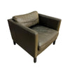 A single upholstered armchair with a square back and arms, shown at an angle on a plain white background. The chair is upholstered in a distressed taupe-brown leather or faux leather, with dark wooden legs.