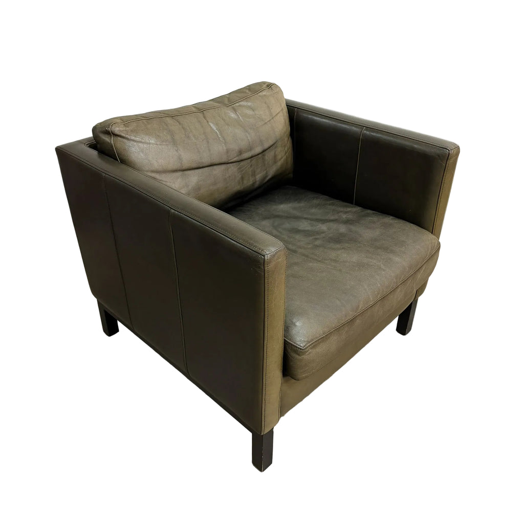 A single upholstered armchair with a square back and arms, shown at an angle on a plain white background. The chair is upholstered in a distressed taupe-brown leather or faux leather, with dark wooden legs.