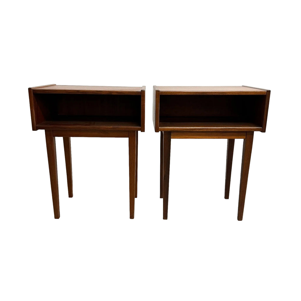 A pair of mid-century modern wooden side tables with open shelving and tapered legs, shown against a plain white wall and concrete floor.