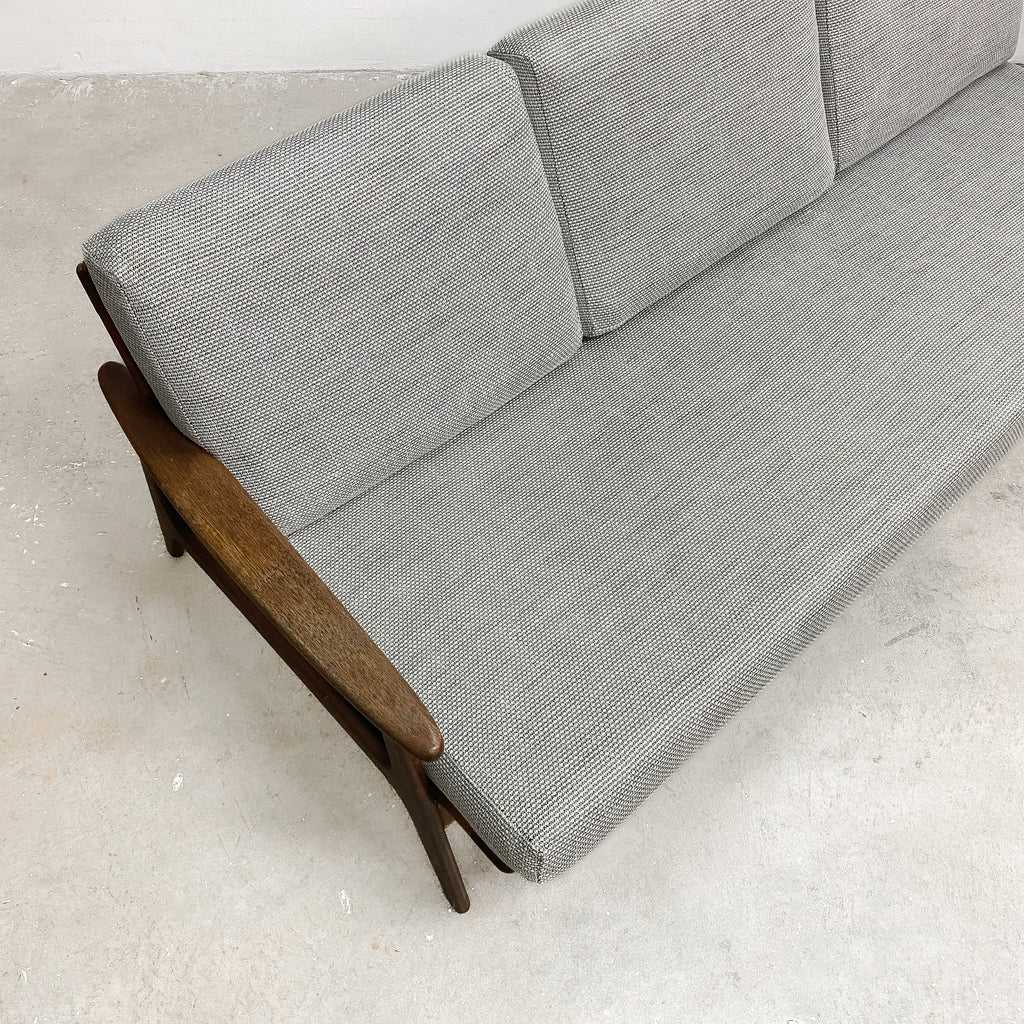 Gray sofa with wooden armrests on a light gray floor