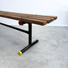 Wooden bench with black metal legs on a concrete floor