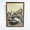 Framed artwork of a cityscape with a boat on water, on a white wall.